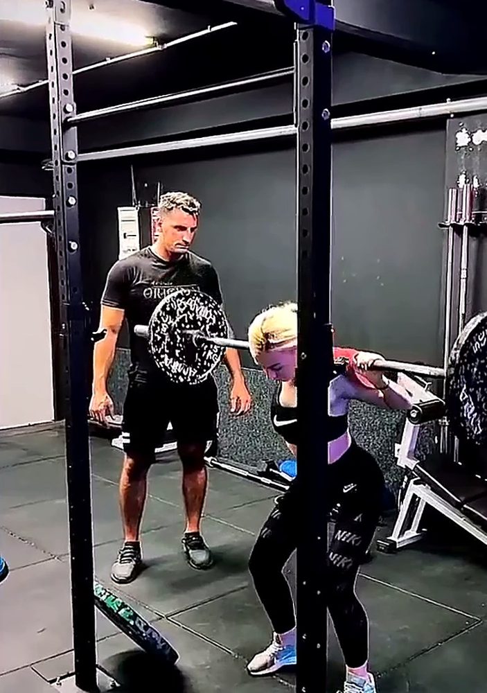 Billy spotting a client during a barbell back squat